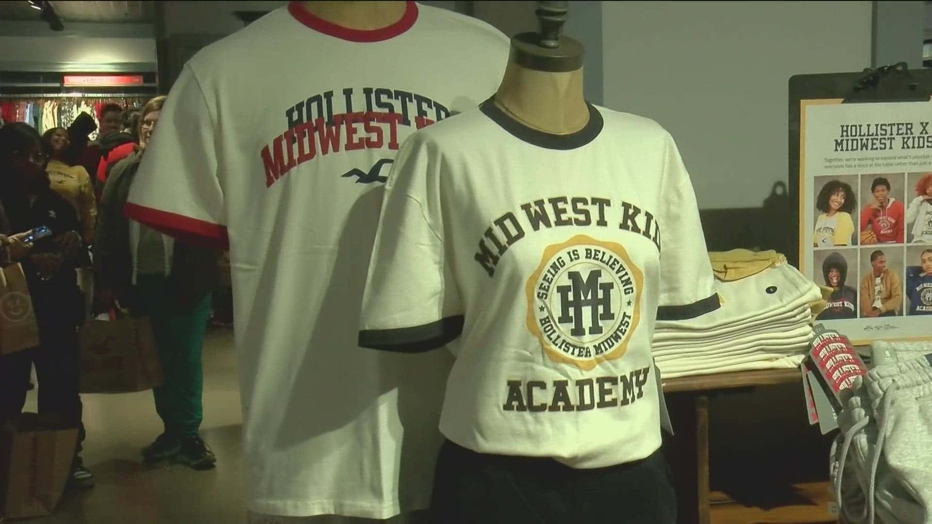 Hollister 桌布 壁紙 — 兩個模特兒展示Hollister Midwest Kids T恤，背景有顧客在瀏覽。