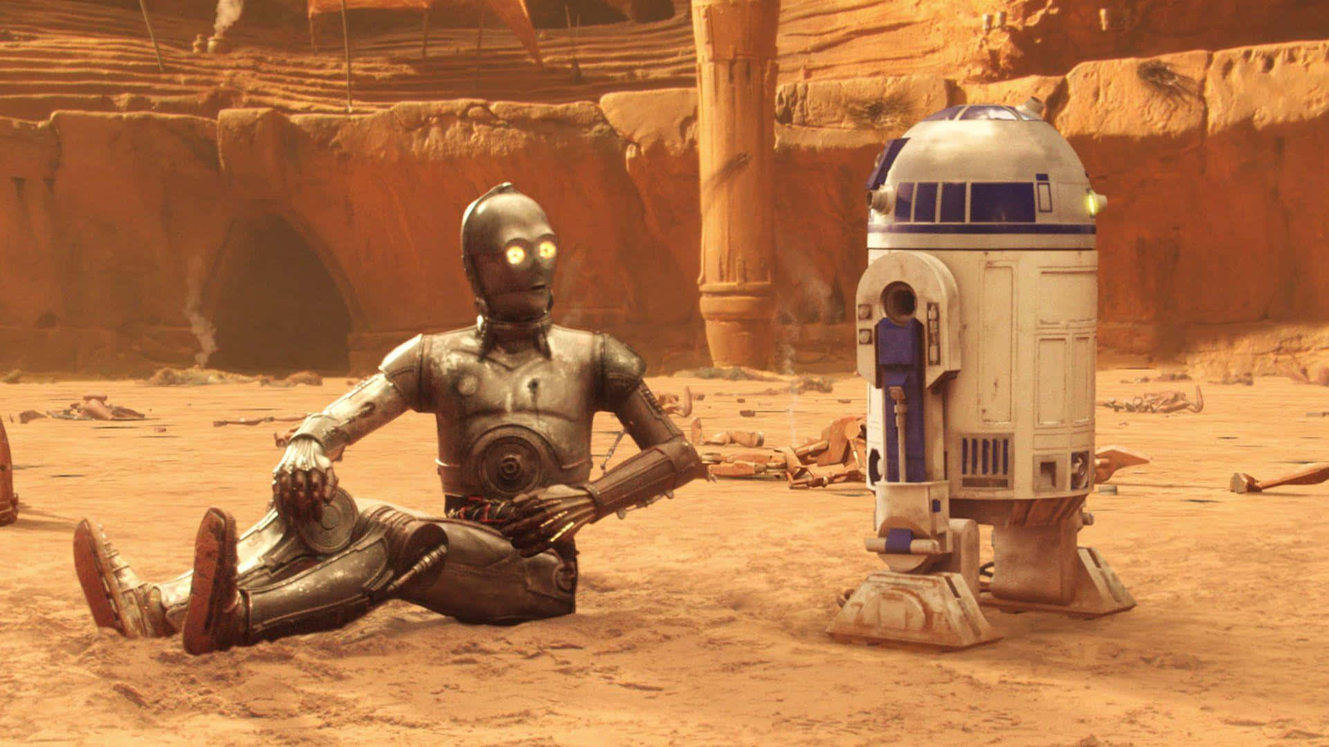 C-3po 桌布 壁紙 — 兩個機器人C-3PO和R2-D2坐在一個佈滿灰塵的沙漠峽谷中，周圍有橙色岩石結構和散落的碎片。