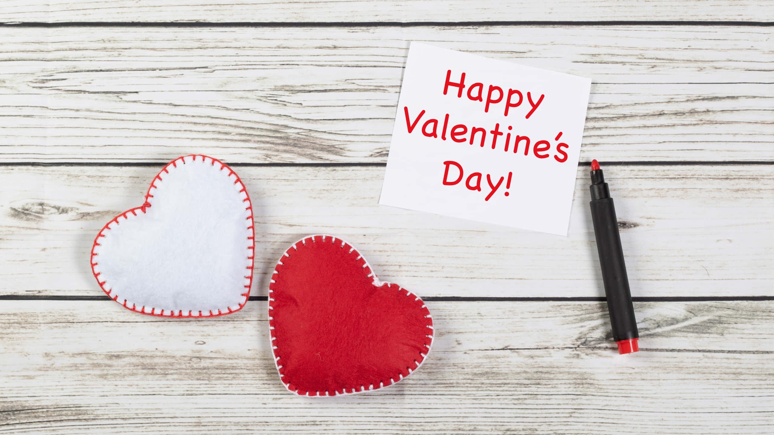 Happy Valentines Day 桌布 壁紙 — 兩個氈製心形和手寫情人節便條放在經風化的白色木質表面上。
