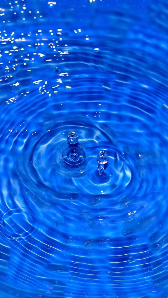 Cool Water 桌布 壁紙 — 兩個水滴懸浮在充滿活力的藍色水池上方，形成同心漣漪的特寫。