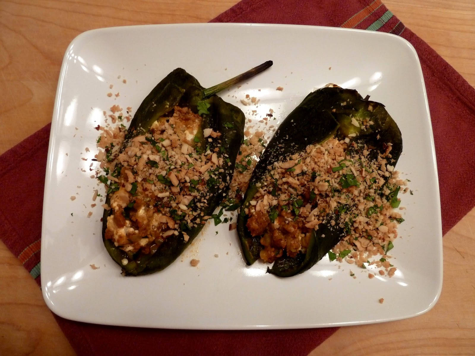 Delicious Food 桌布 壁紙 — 兩個烤波布拉諾辣椒，填入美味餡料，上面撒有碎堅果和香草，放在白色盤子上。