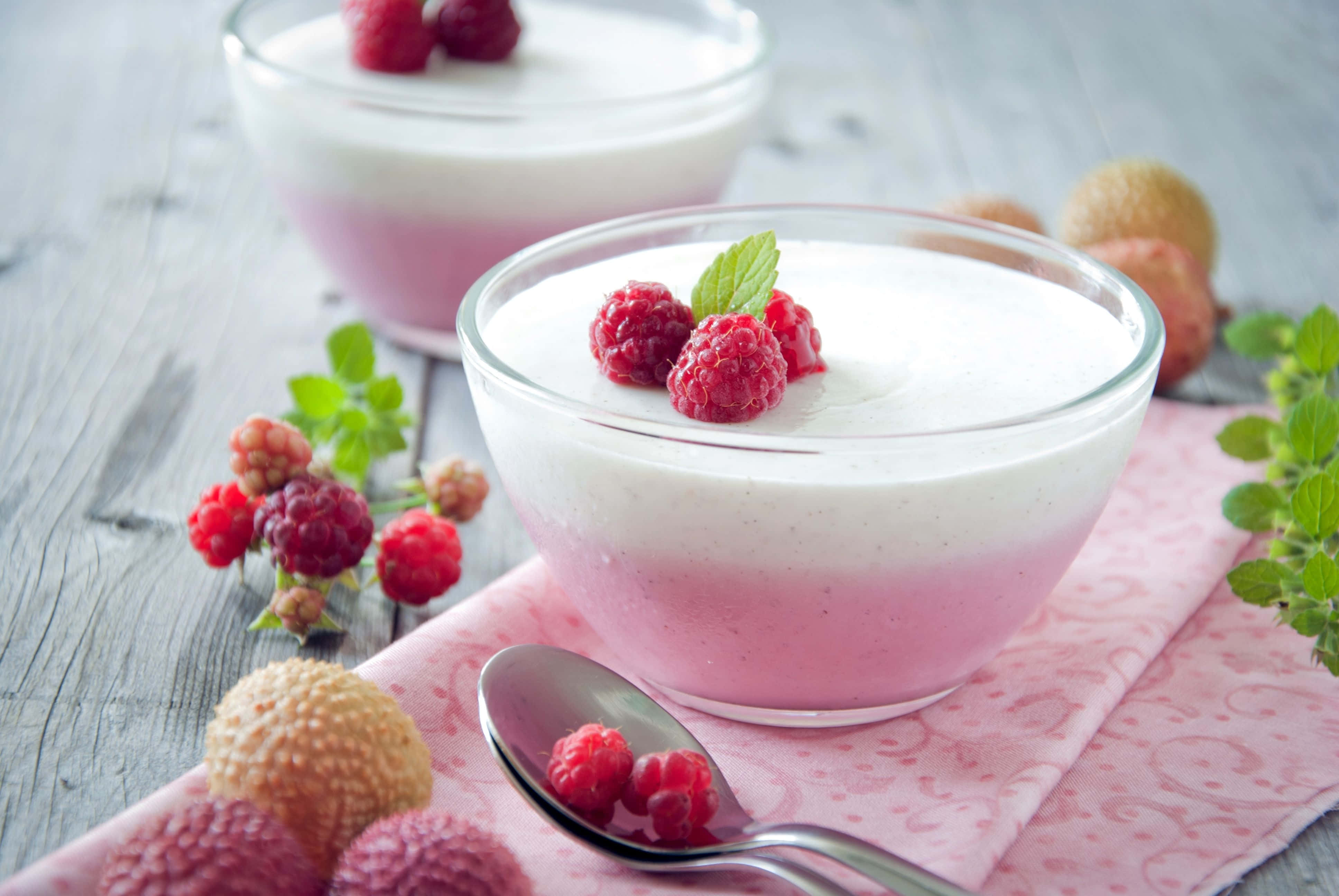 Spring Desserts 桌布 壁紙 — 兩個玻璃碗盛裝粉紅和白色分層優格，上面放上新鮮覆盆子和薄荷，置於鄉村風木桌上。