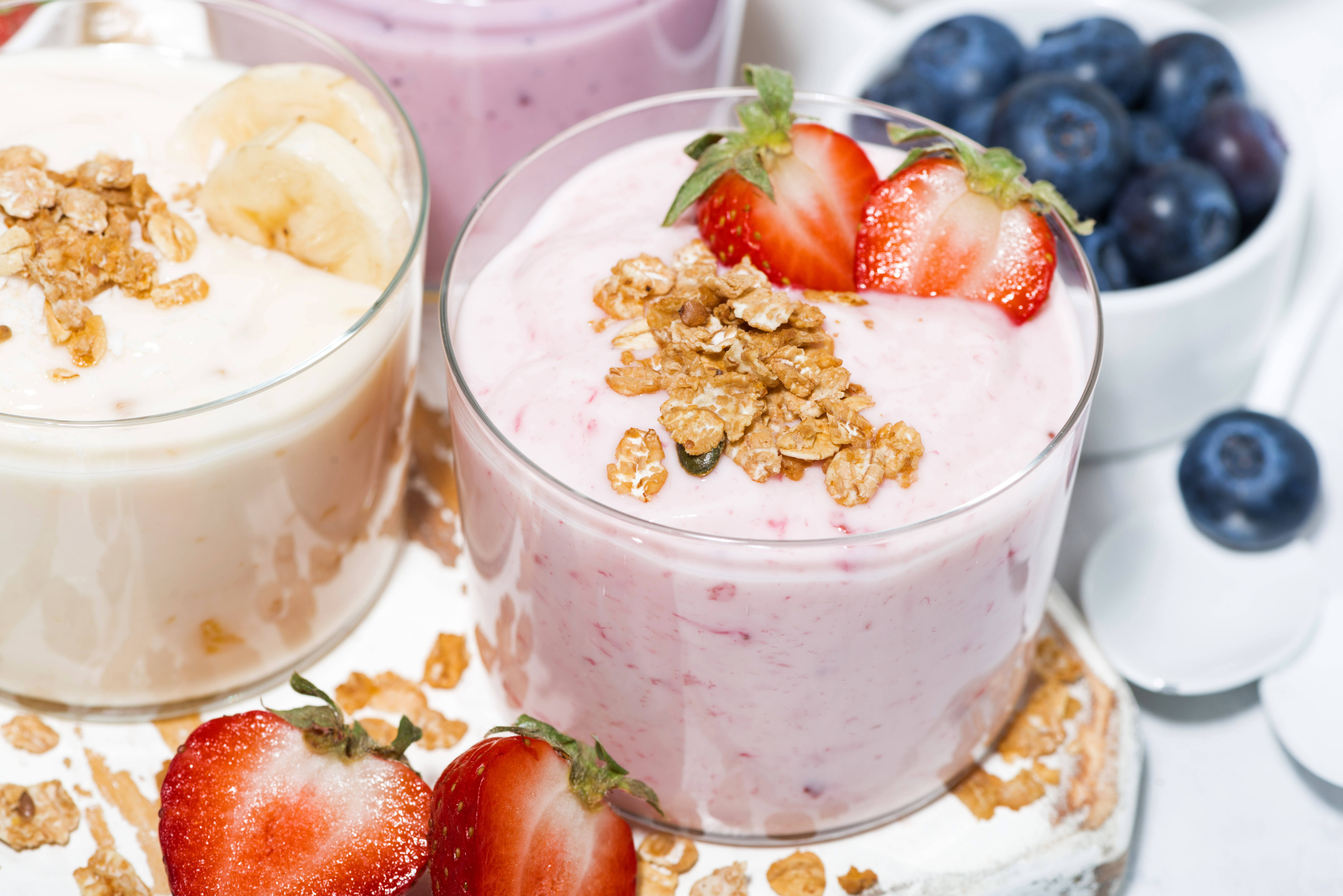 Yogurt 桌布 壁紙 — 兩個玻璃罐裝滿了奶油優格，上面撒上燕麥片和新鮮草莓和藍莓。