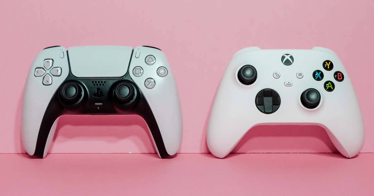 Xbox 桌布 壁紙 — 兩個現代遊戲控制器 PlayStation 和 Xbox 並排放置在柔軟的粉紅色背景上。