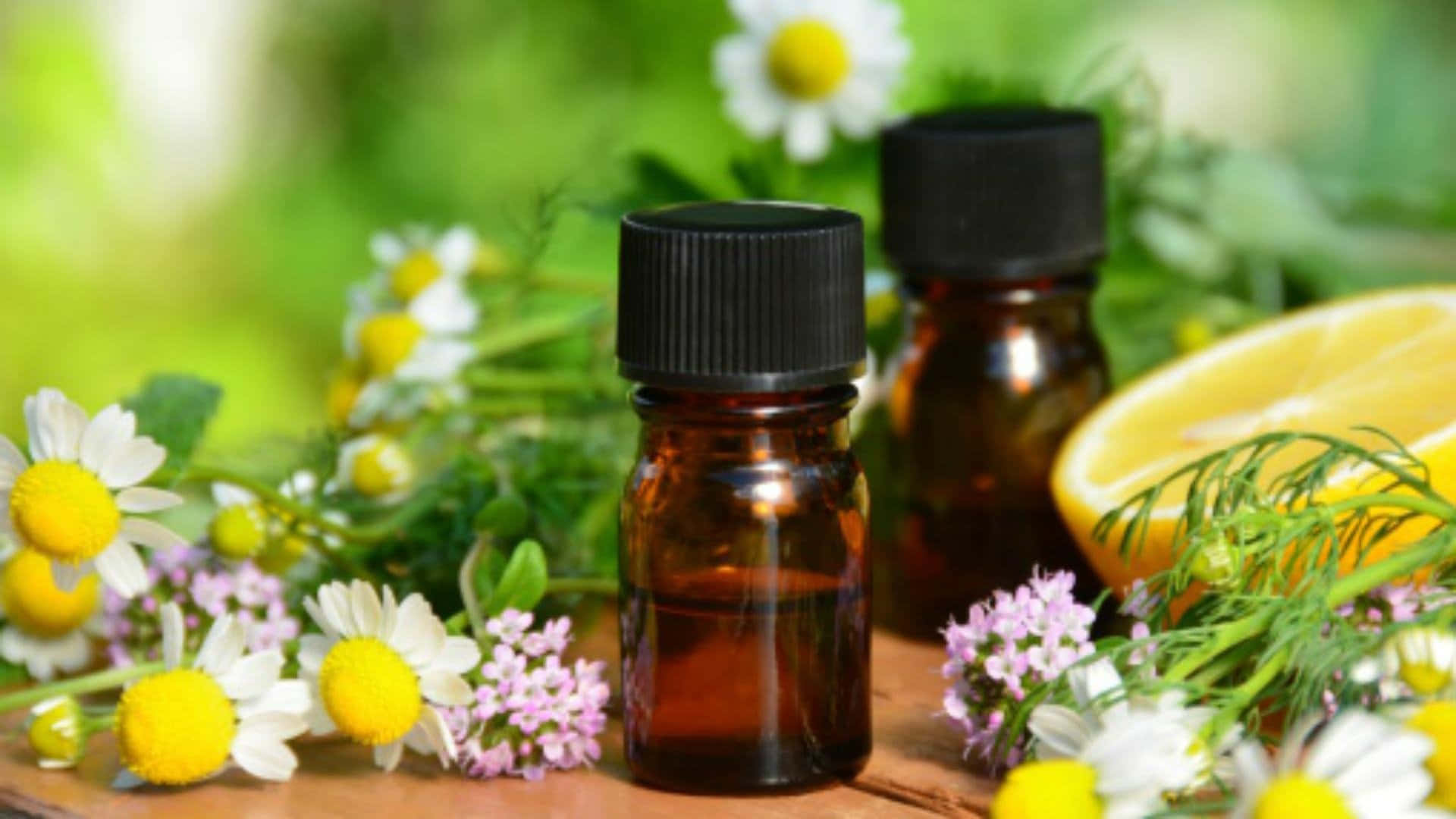 Aromatherapy 桌布 壁紙 — 兩個琥珀色精油瓶放在木質表面上，周圍是新鮮的洋甘菊、檸檬和蒔蘿。