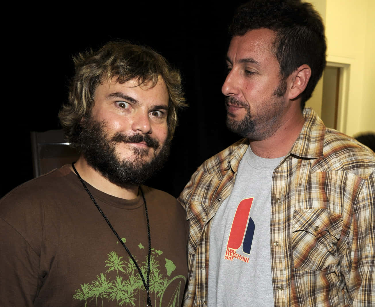 jack black 桌布 壁紙 — 兩個男人並肩而立，一個睜大眼睛留鬍鬚，另一個穿著格紋襯衫在室內望向別處。