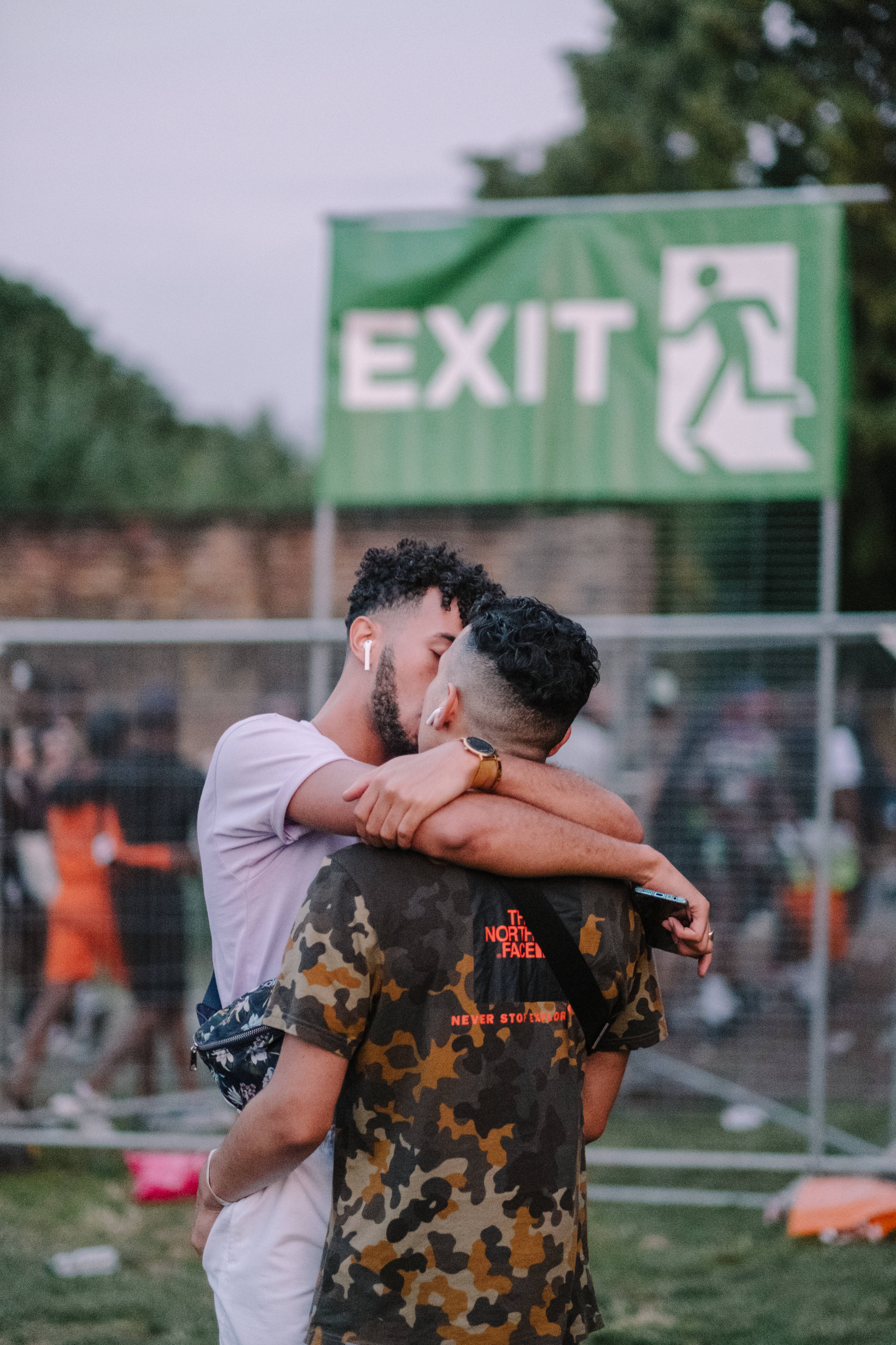 men kissing 桌布 壁紙 — 兩個男人在戶外活動的綠色出口標誌前熱情擁抱和親吻。