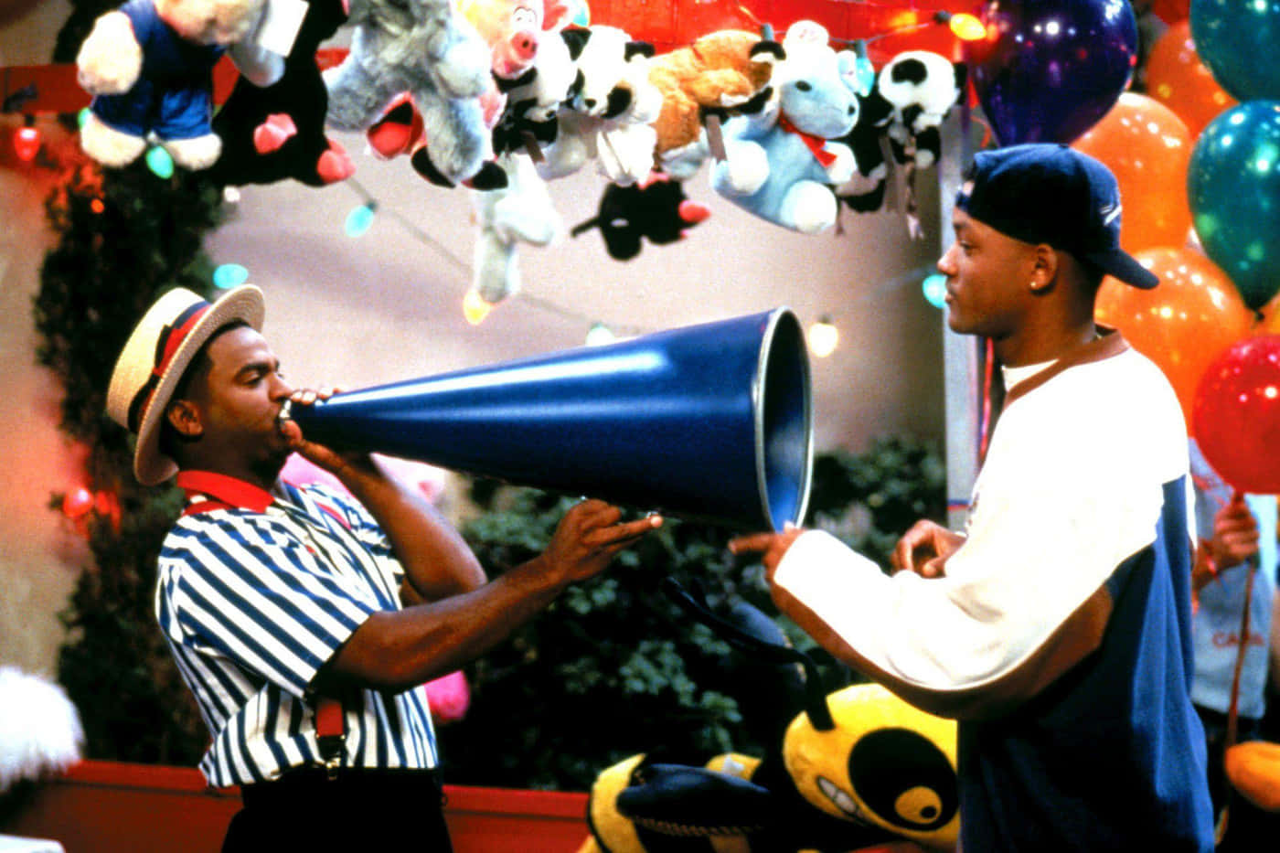 fresh prince 桌布 壁紙 — 兩個男人在掛滿絨毛玩偶和彩色氣球的節慶室內環境中與一個藍色擴音器互動。