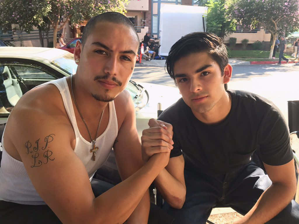 Celebrity 桌布 壁紙 — 兩個男人在明亮的陽光下，於白色汽車附近戶外擺姿勢，雙手緊握。
