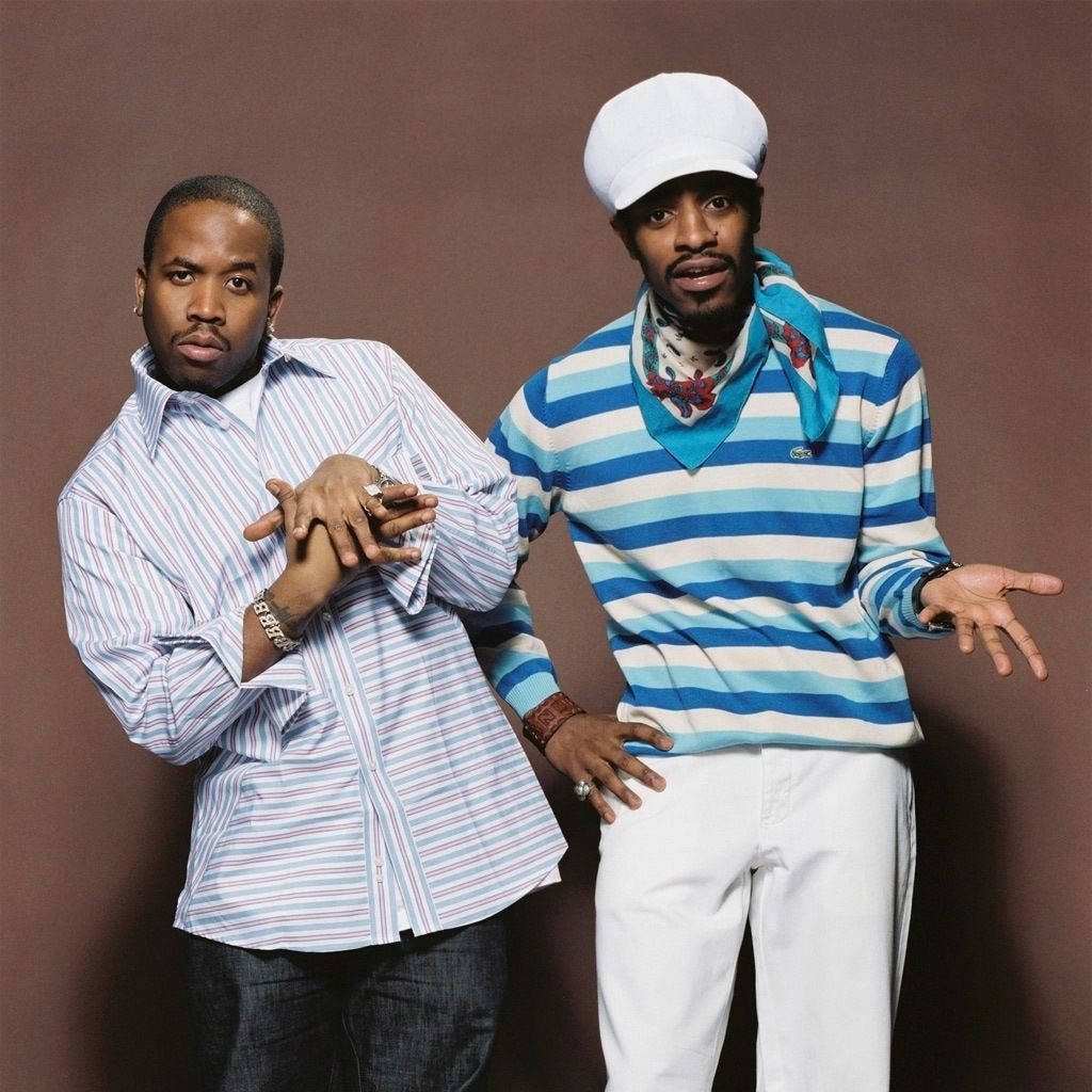 hiphop 桌布 壁紙 — 兩個男人在棕色背景前自信地擺姿勢，一個穿條紋襯衫，另一個穿藍色條紋毛衣和白色帽子。