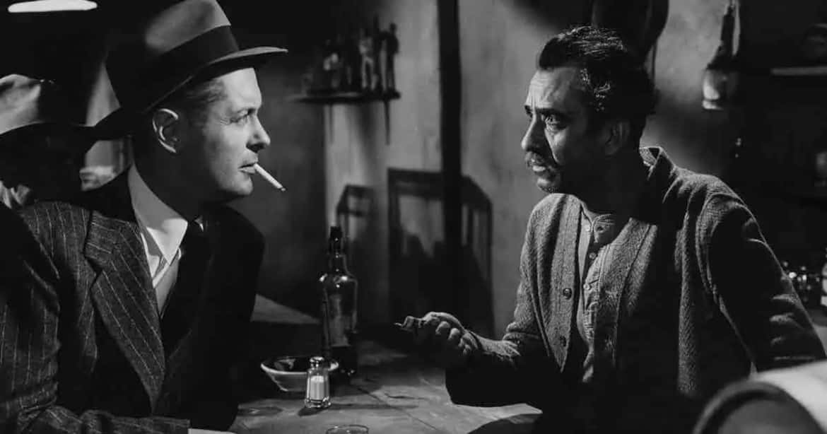 Film Noir 桌布 壁紙 — 兩個男人在燈光昏暗的1940年代酒吧中，隔著一張放有酒瓶的桌子激烈交談，煙霧在他們之間繚繞。