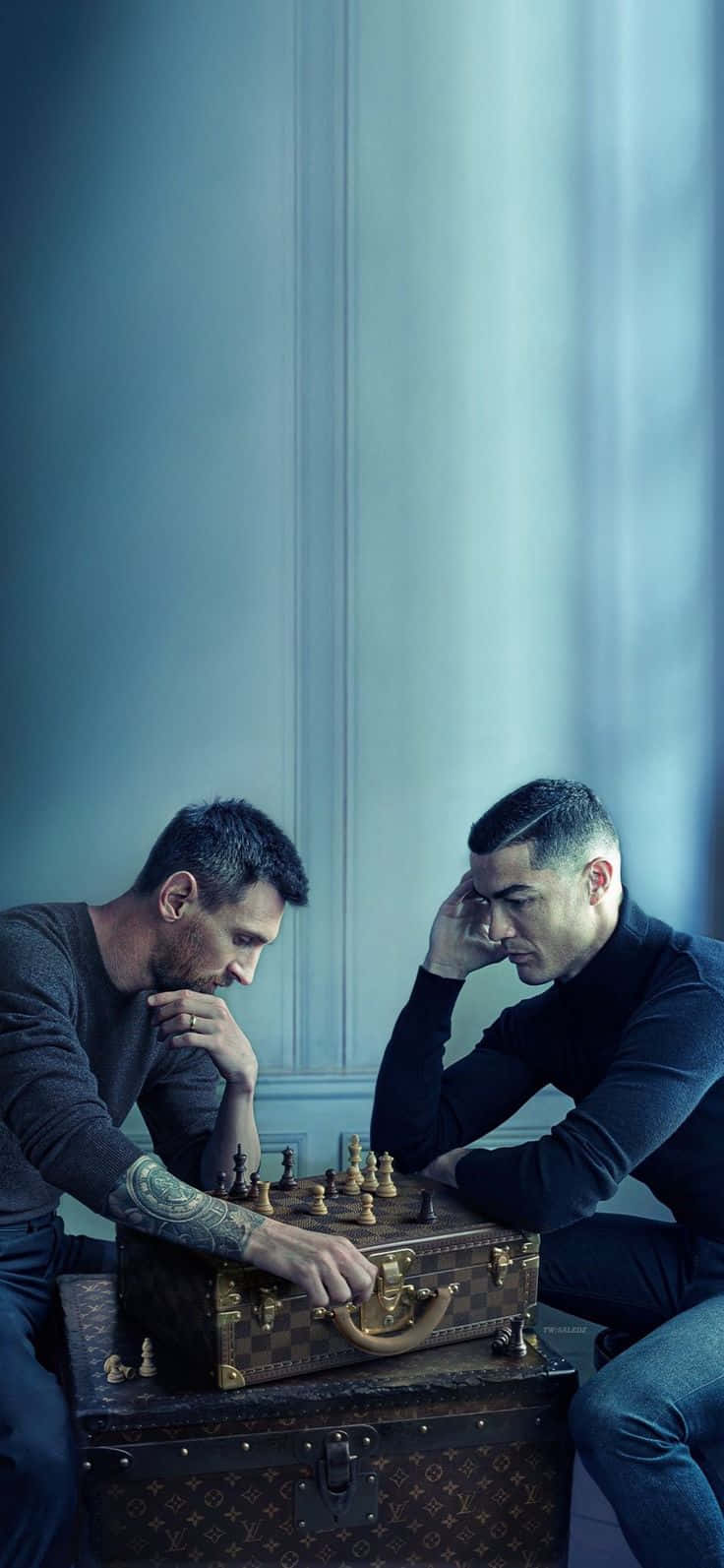 Messi And Ronaldo 4K 桌布 壁紙 — 兩個男人專注於在一個復古路易威登行李箱上進行的西洋棋遊戲，房間色調為冷藍色。