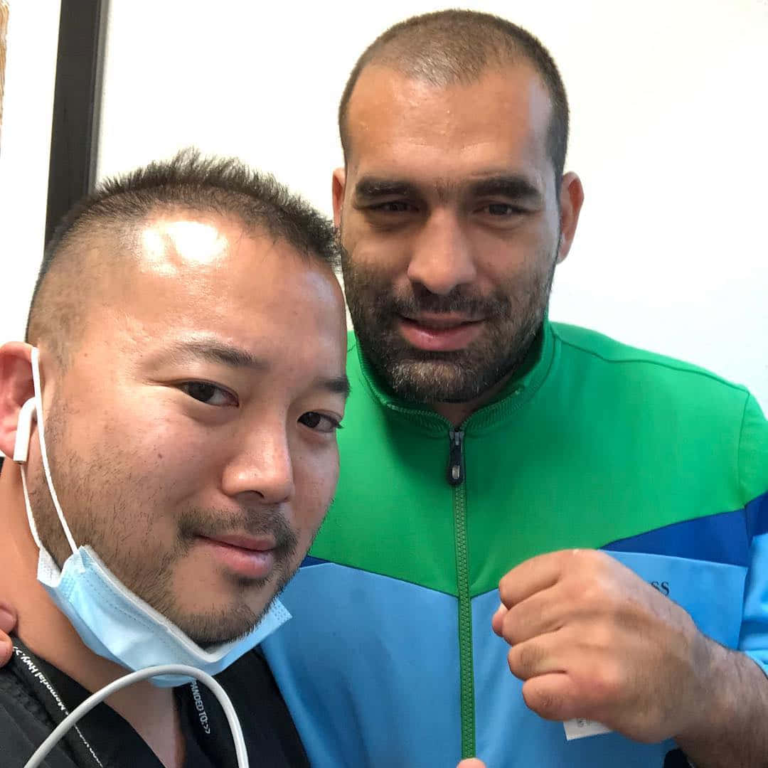 MMA 桌布 壁紙 — 兩個男人擺姿勢自拍，一個拉下口罩，另一個穿著綠色和藍色外套握拳。