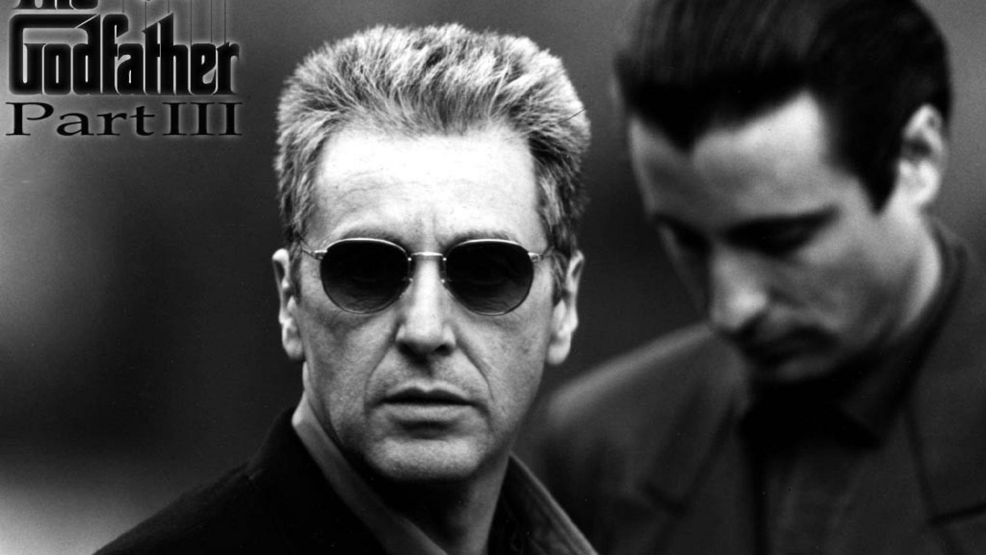 The Godfather 桌布 壁紙 — 兩個男人的黑白特寫，一個戴著太陽眼鏡，另一個低著頭，表情嚴肅。