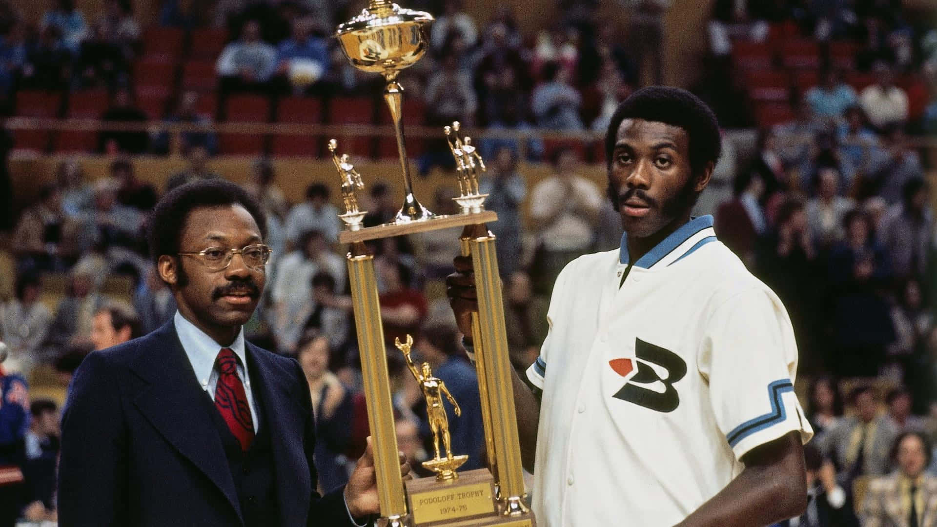 NBA 桌布 壁紙 — 兩個男人站在擠滿人的場館裡，手持一個大型金色獎盃，獎盃底座上有雕像。