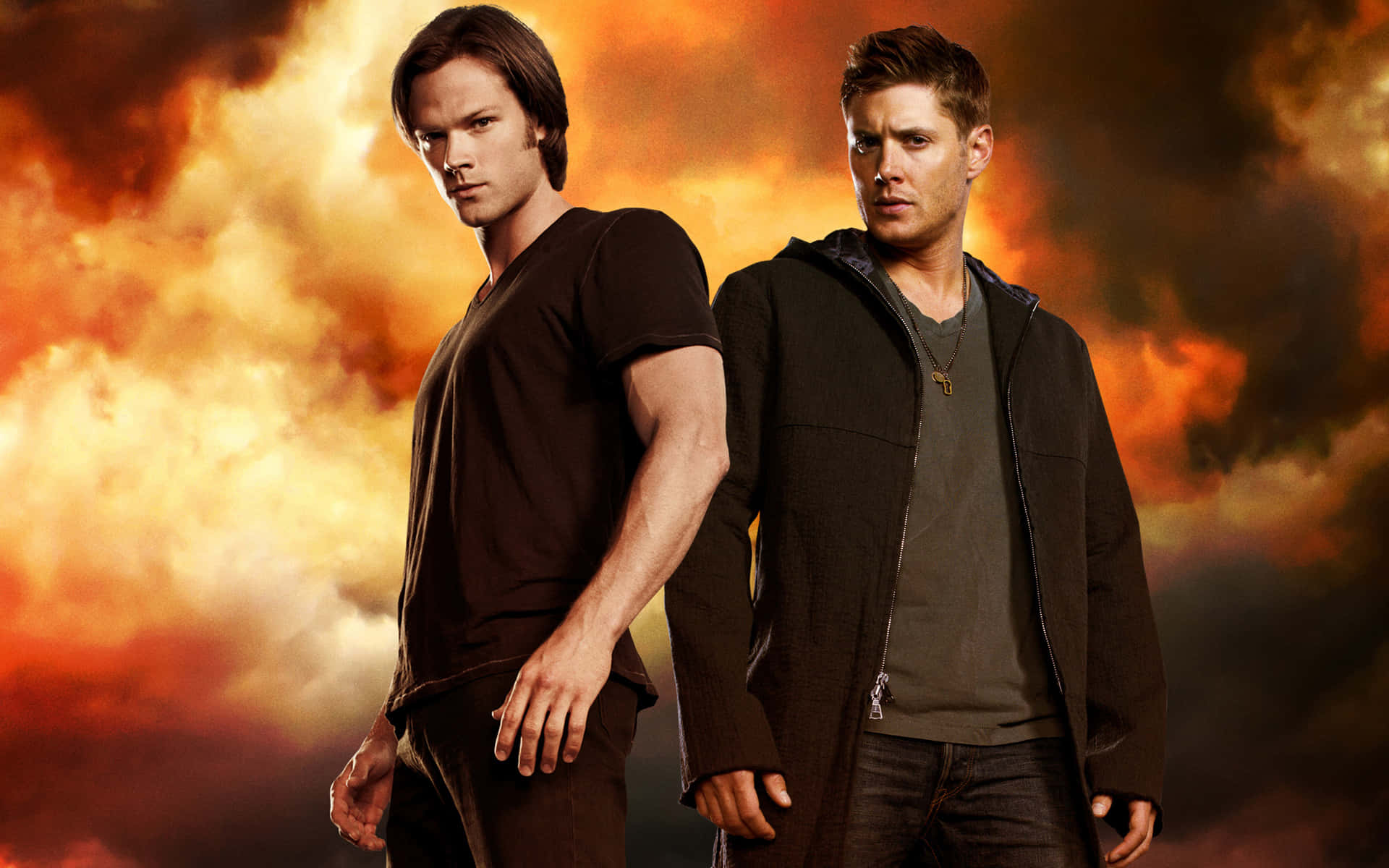 dean winchester 桌布 壁紙 — 兩個男人自信地站在火橙色和紅色的暴風雨天空下，表情強烈。