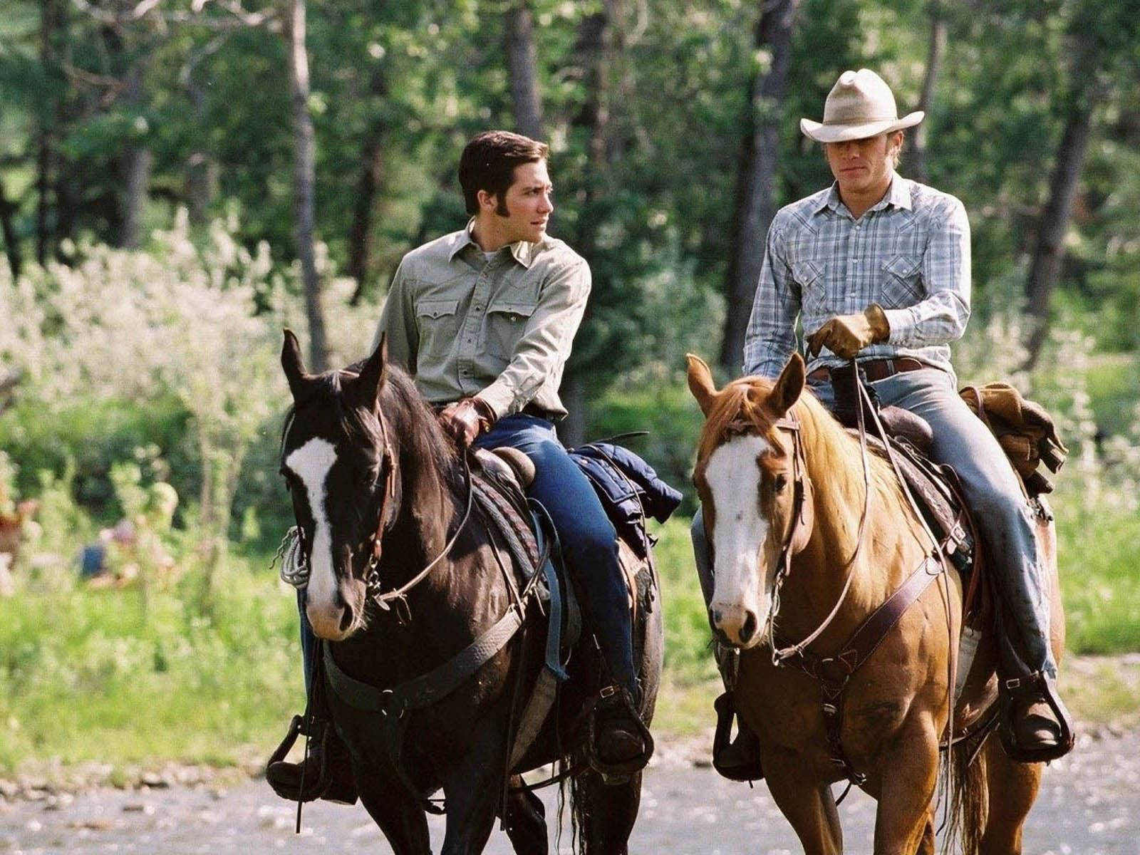brokeback mountain 桌布 壁紙 — 兩個男人騎著馬沿著森林小徑前行，陽光透過高大的樹木灑下斑駁的光影。