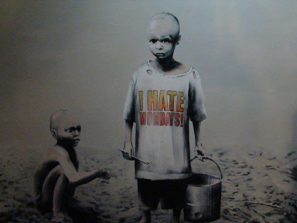 Banksy 桌布 壁紙 — 兩個瘦弱的孩子站在貧瘠的土地上，其中一個穿著破爛的襯衫，上面寫著「我討厭星期一！」，同時拿著一個水桶。