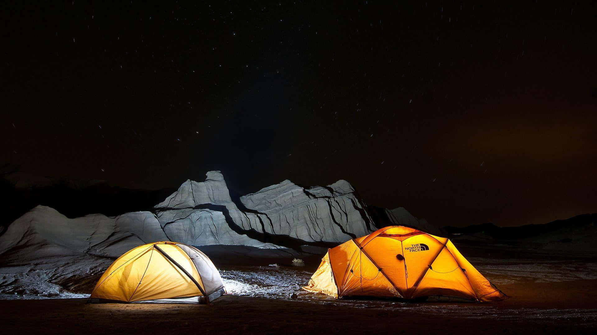 Beach Camping 桌布 壁紙 — 兩個發光的帳篷在星空下照亮了積雪的山地露營地。