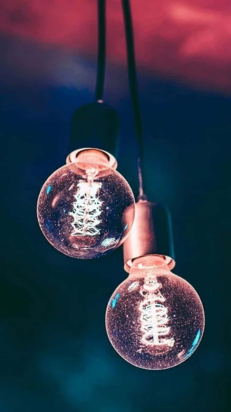 Light 桌布 壁紙 — 兩個發光的復古燈絲燈泡懸掛在戲劇性的紅色和藍色暮色天空中。