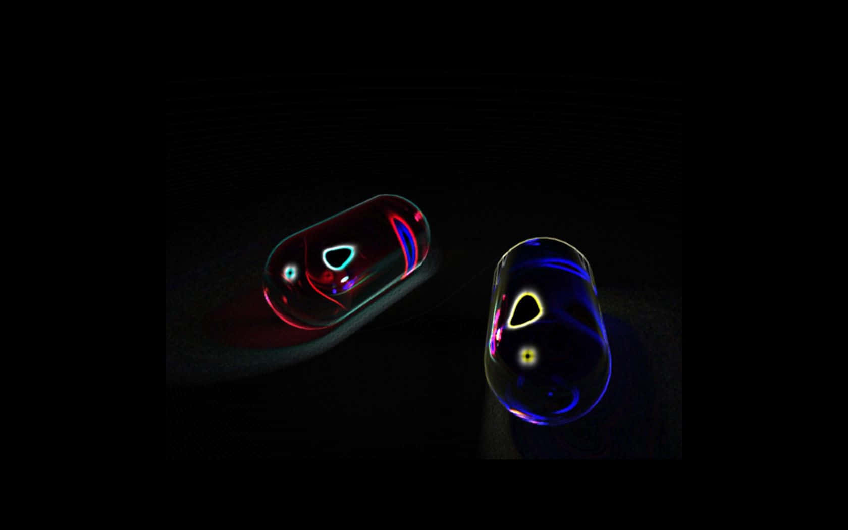 pills 桌布 壁紙 — 兩個發光的玻璃膠囊在黑暗中漂浮，將霓虹紅、藍、黃光折射成抽象圖案。