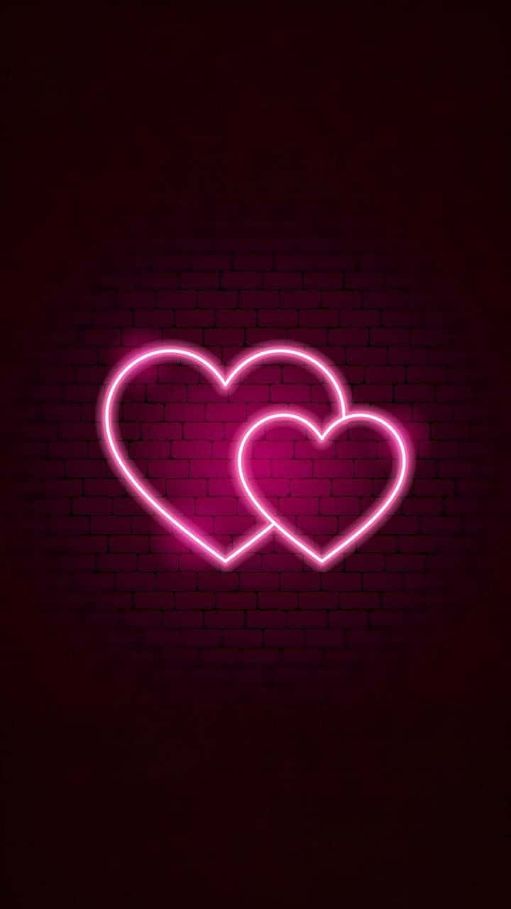 Pink Neon Aesthetic 桌布 壁紙 — 兩個發光的粉紅色霓虹心形交織在深色磚牆背景下。