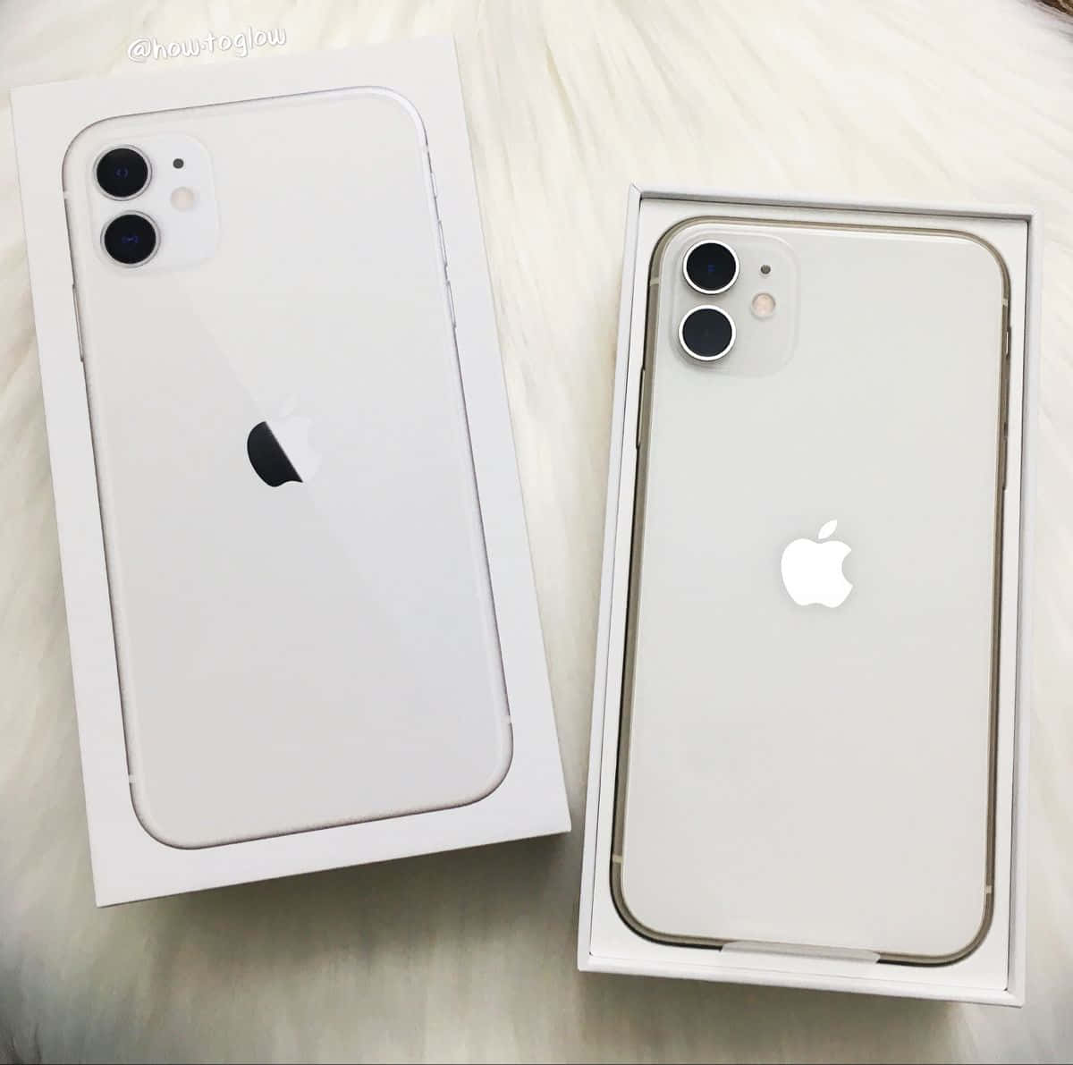iPhone 12 桌布 壁紙 — 兩個白色iPhone 11盒子內有手機，放在毛絨絨的白色表面上。