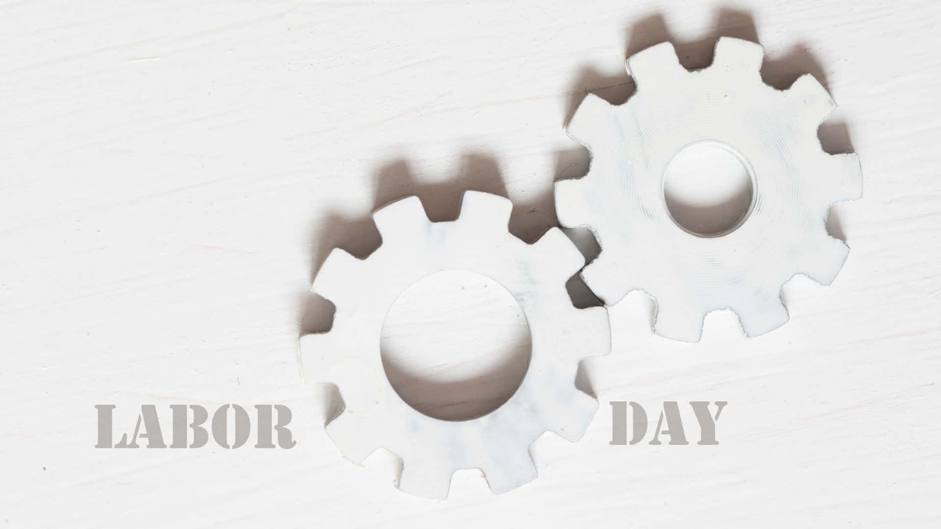 勞動節 桌布 壁紙 — 兩個白色大理石齒輪帶有文字 labor day，在帶紋理的白色表面上投射出柔和陰影。