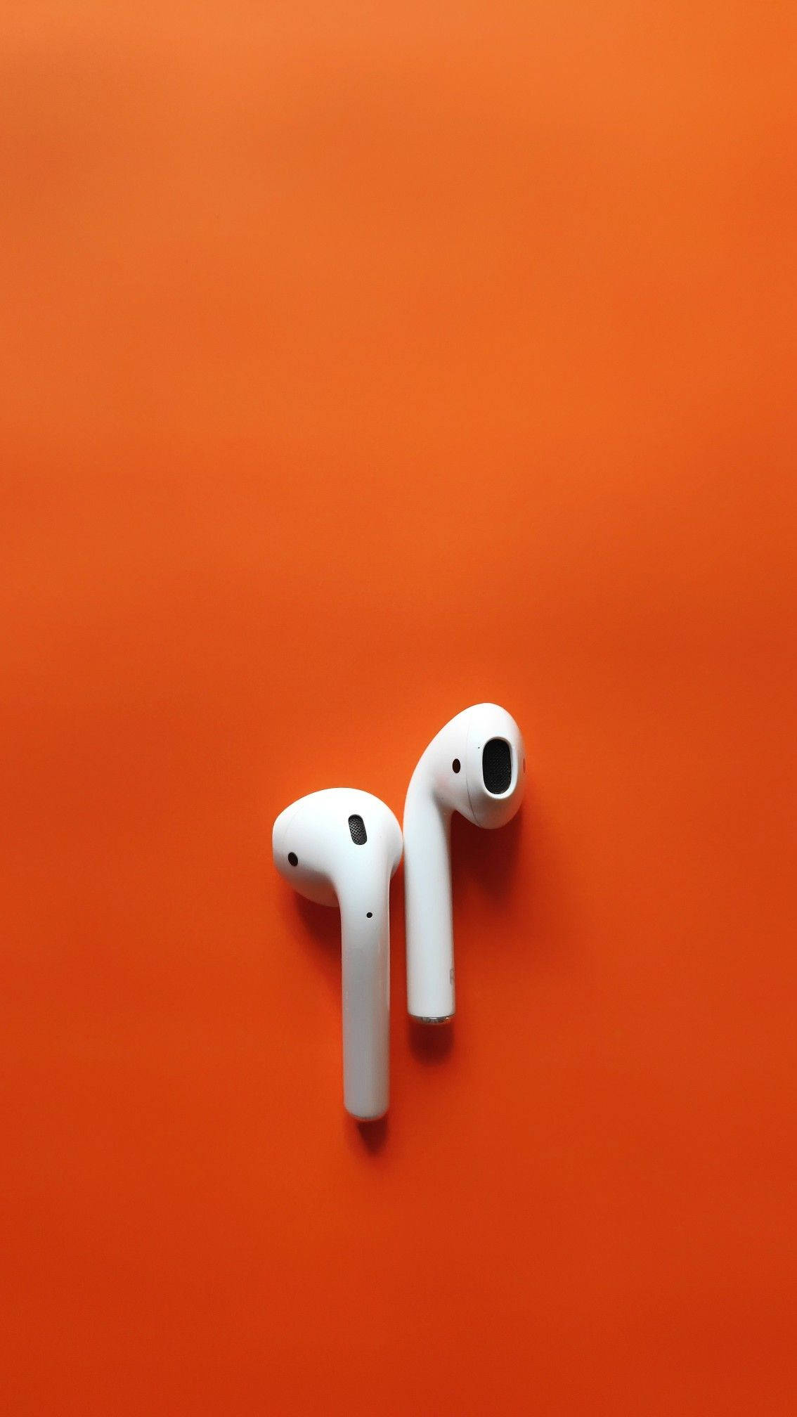 Airpods 桌布 壁紙 — 兩個白色無線耳塞放在純橙色背景上，形成極簡的平鋪構圖。