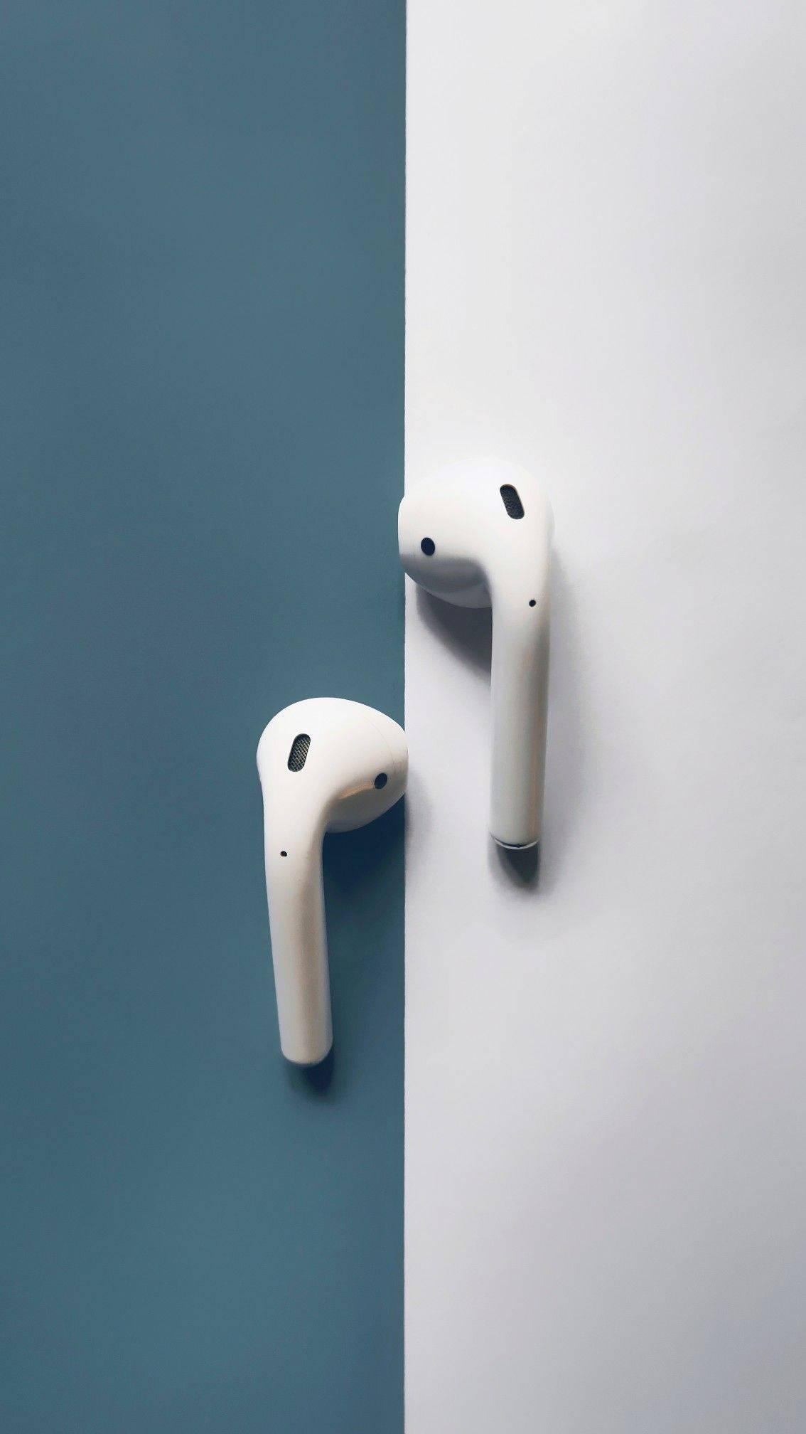 AirPods 桌布 壁紙 — 兩個白色無線耳塞靠著一分為二的青綠色和白色背景，呈現極簡構圖。
