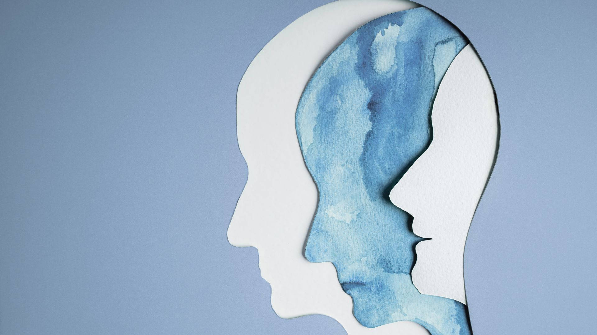 mind 桌布 壁紙 — 兩個白色紙張頭部剪影重疊，在其中一個側面輪廓內顯露出藍色水彩大腦。