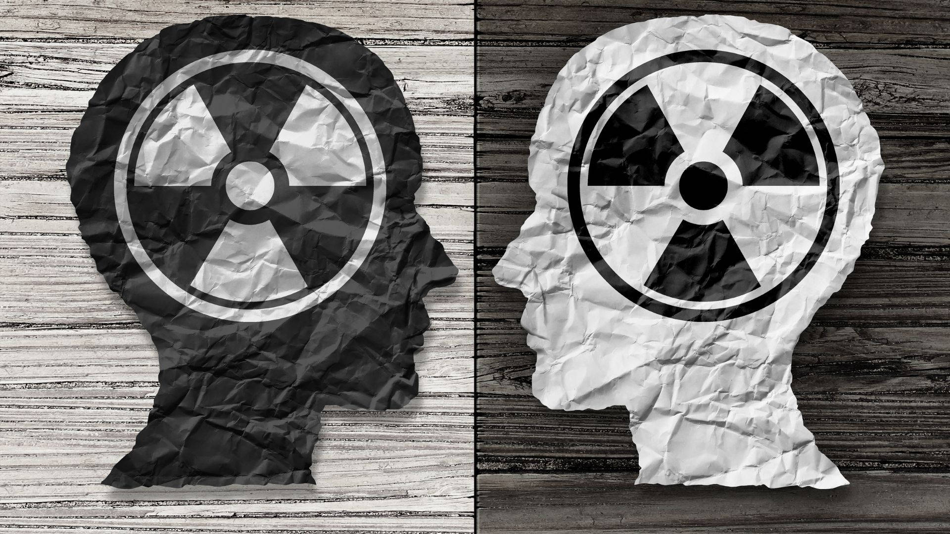 Brain 桌布 壁紙 — 兩個皺巴巴的紙質頭部剪影，帶有輻射標誌，放在風化的木質表面上。