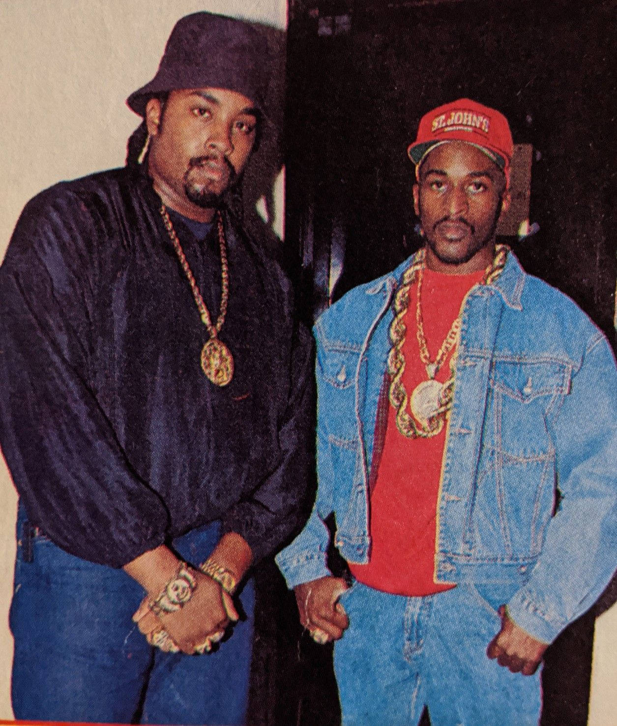 Rappers 桌布 壁紙 — 兩個穿著90年代嘻哈服裝的男人，戴著金鏈和牛仔布，自信地靠在素色牆上擺姿勢。