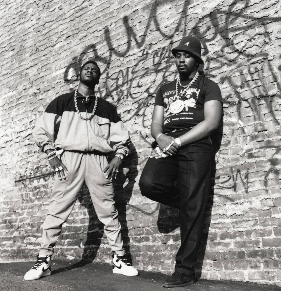Rappers 桌布 壁紙 — 兩個穿著90年代街頭服飾的男人在佈滿塗鴉的磚牆前自信地擺姿勢，黑白風格。