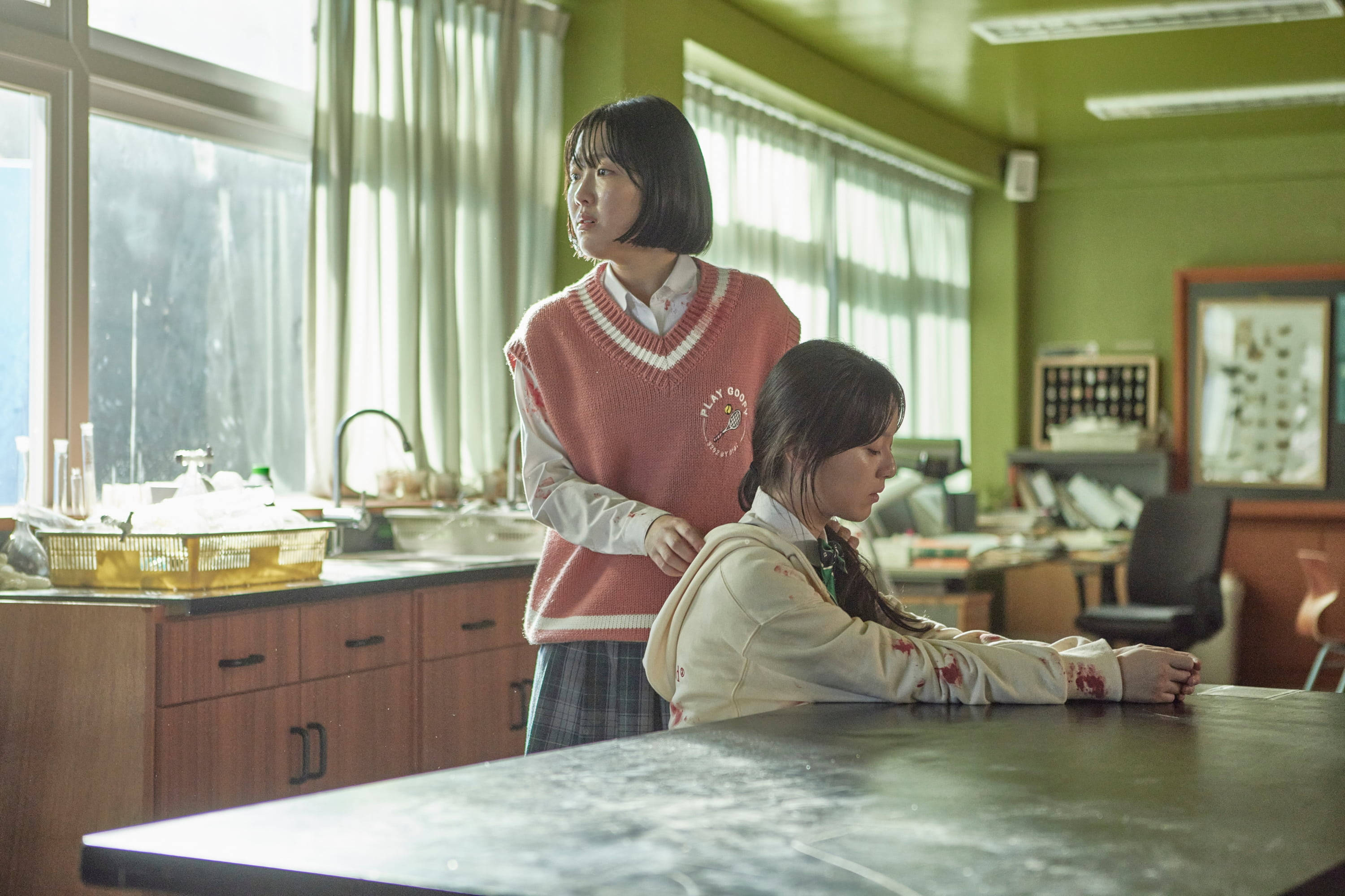 恐怖 桌布 壁紙 — 兩個穿著校服的女孩子站在陽光照射、綠色牆壁的教室裡，其中一個靠在實驗桌上，另一個站在她身後。
