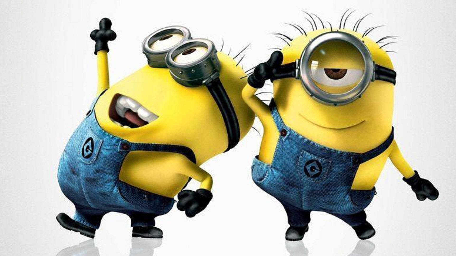 小黃人 桌布 壁紙 — 兩個穿著牛仔布工裝褲的開心黃色Minions在純白色背景前頑皮地擺姿勢。