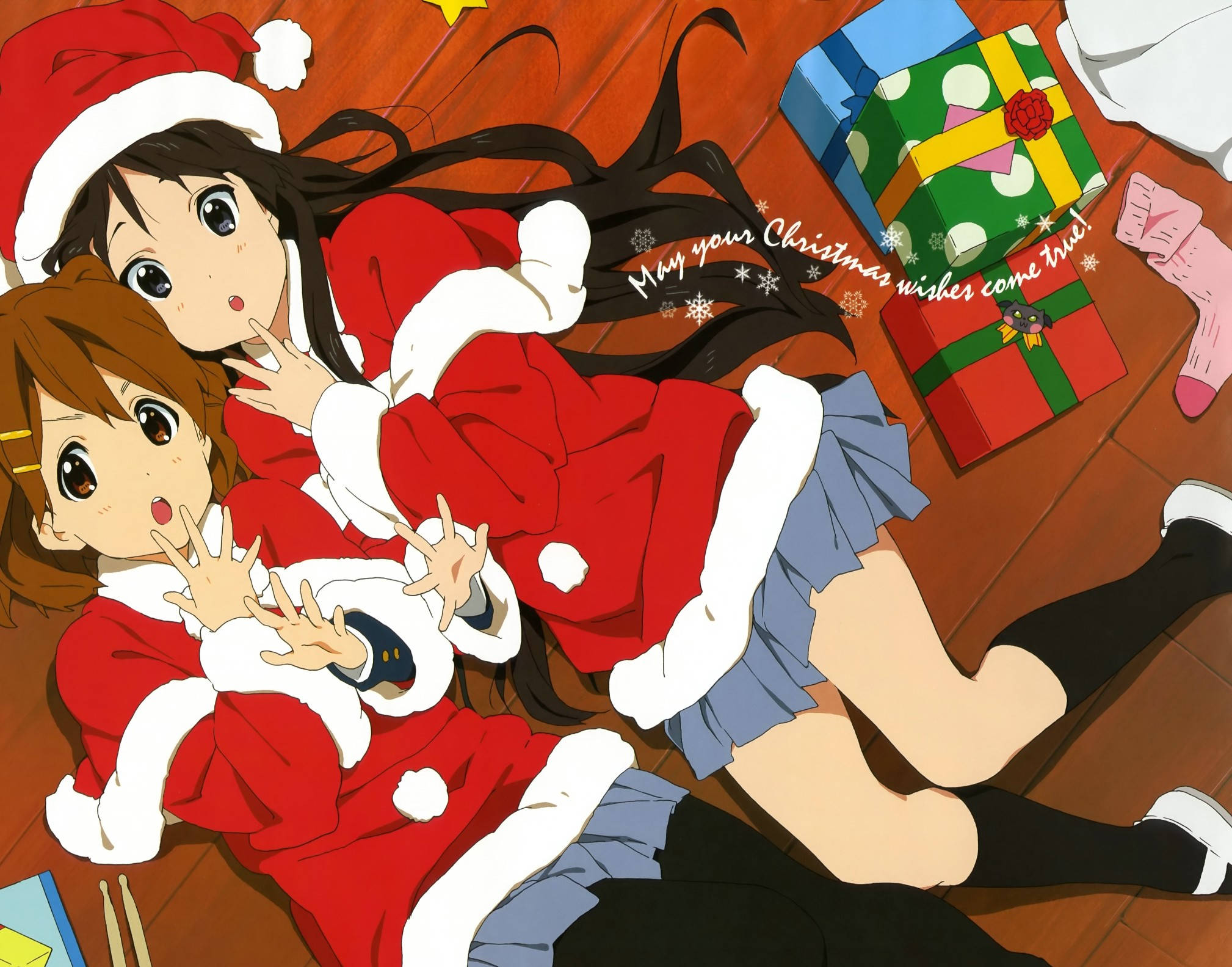 Cute Merry Christmas 桌布 壁紙 — 兩個穿著節日聖誕老人服裝的動漫女孩躺在木地板上，旁邊有色彩繽紛的聖誕禮物和雪花。