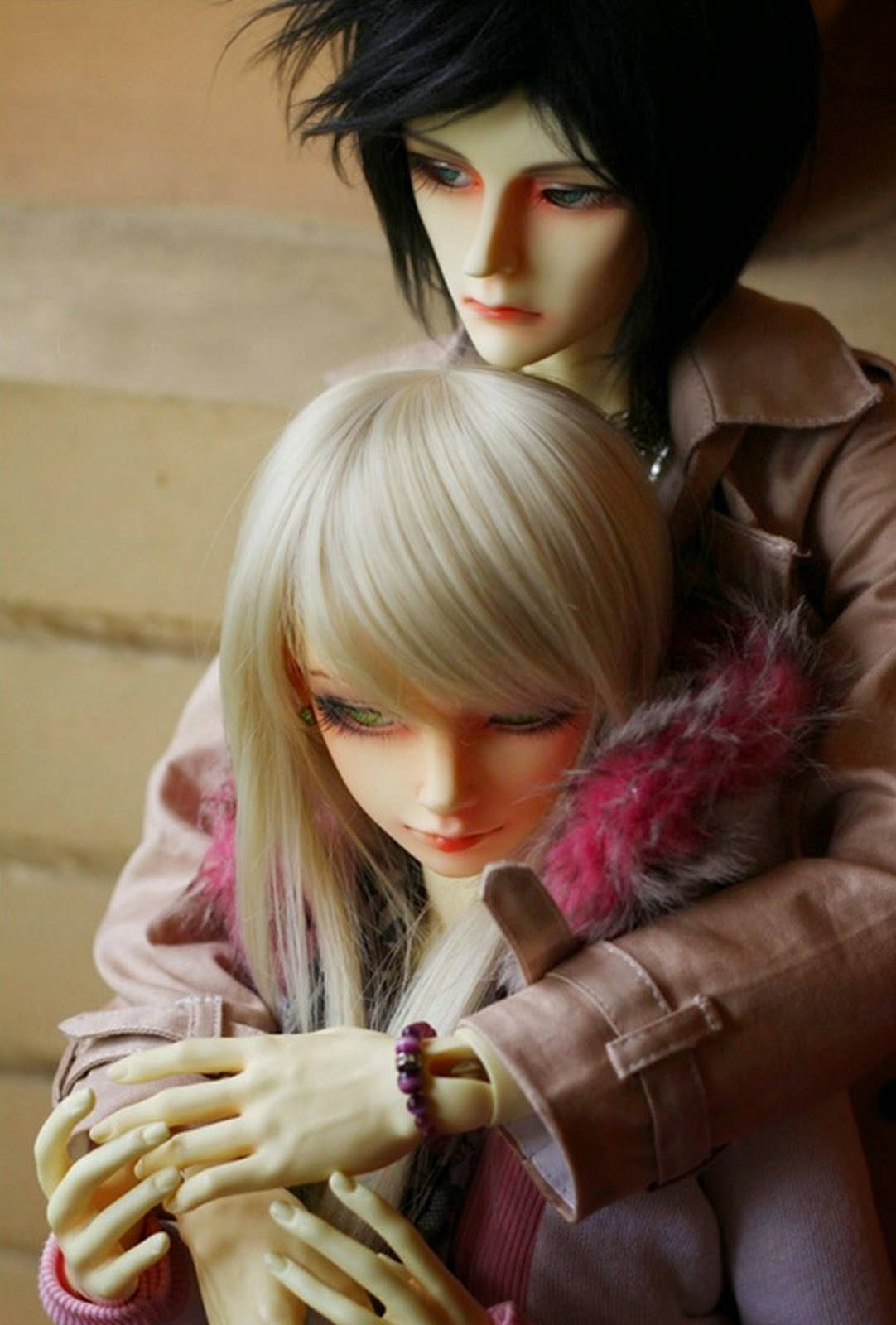 cute doll couple 桌布 壁紙 — 兩個穿著粉紅色外套的動漫風格公仔在溫暖的木質背景下溫柔擁抱。
