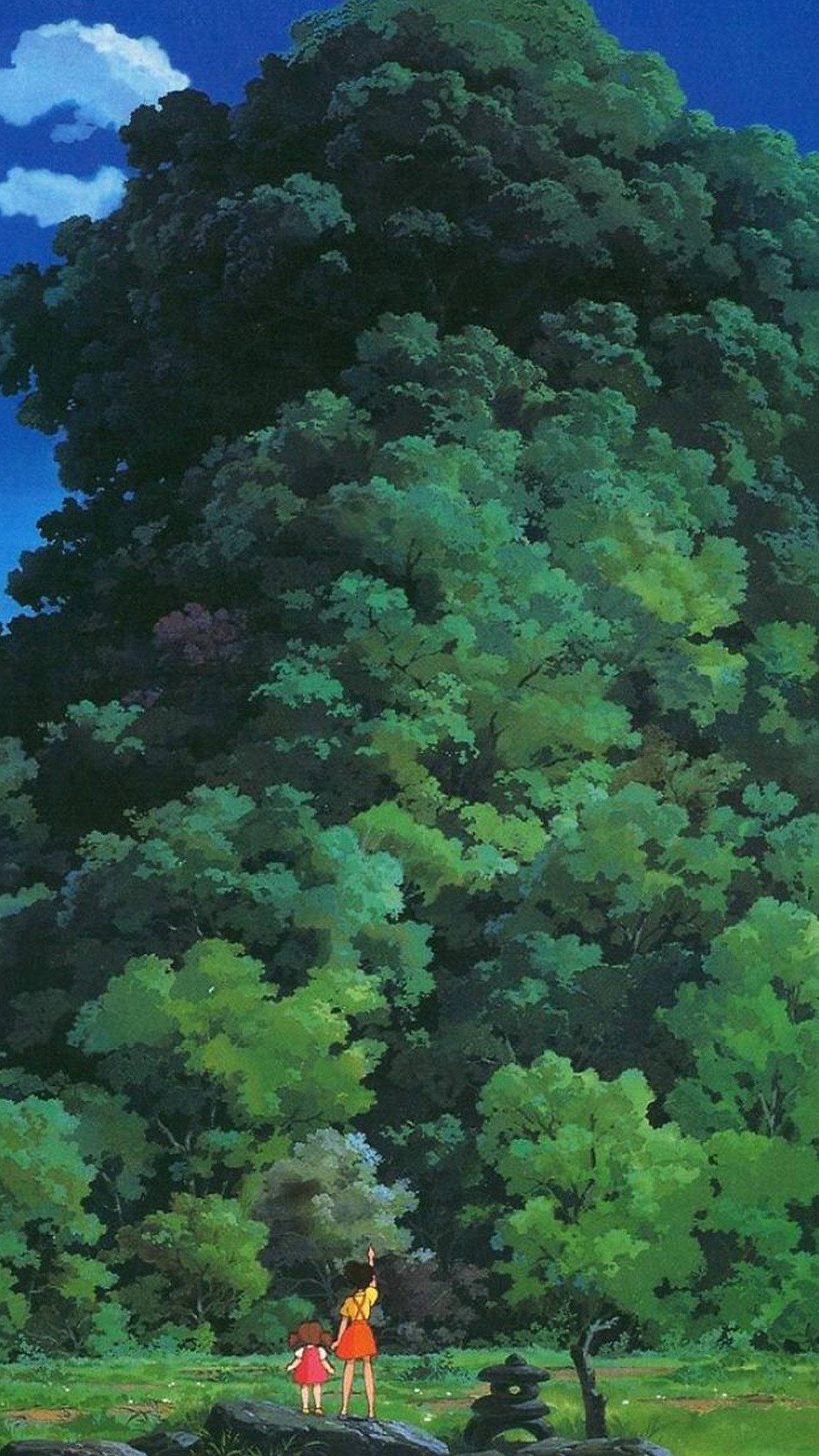 Studio Ghibli iPhone 桌布 壁紙 — 兩個穿著紅色連衣裙的孩子站在一棵巨大的綠色樹木前，背景是晴朗的藍天和蓬鬆的白雲。