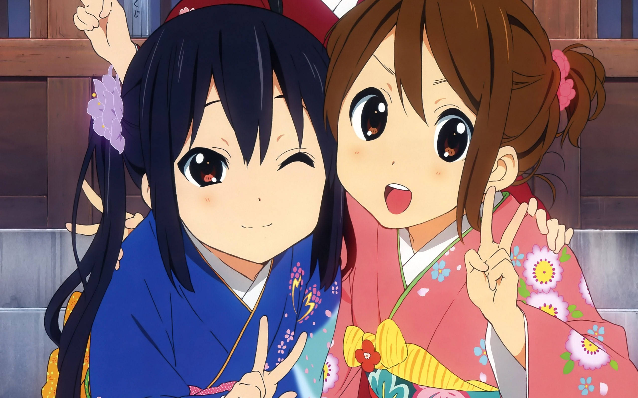 K-on 桌布 壁紙 — 兩個穿著色彩繽紛和服的開朗動漫女孩在木質背景前擺出和平手勢。