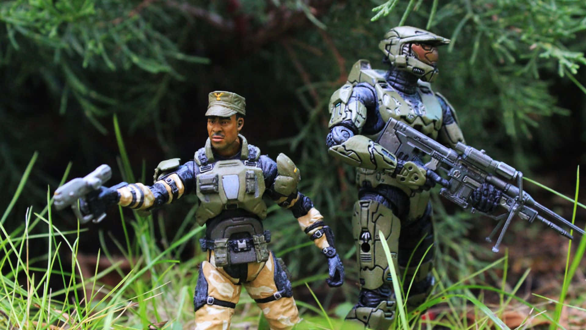 Sergeant Johnson 桌布 壁紙 — 兩個精細的可動人偶，一個穿著軍事裝備，另一個穿著未來風格的盔甲，在茂密森林樹葉中的高綠草中警覺地站立。