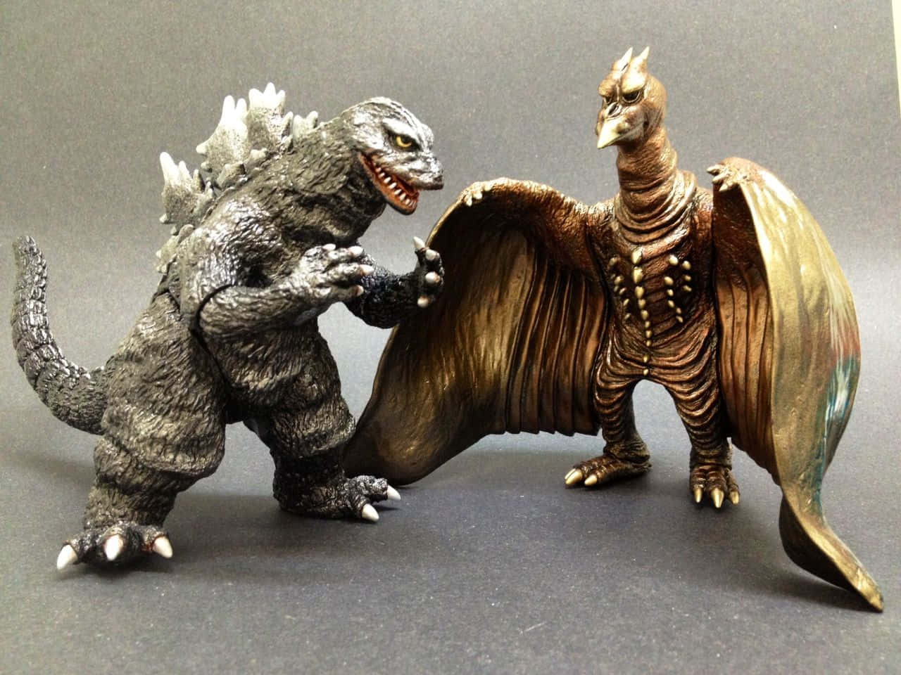 Godzilla Vs Rodan 桌布 壁紙 — 兩個精細的怪獸可動人偶哥吉拉和拉頓在純灰色背景前對峙。