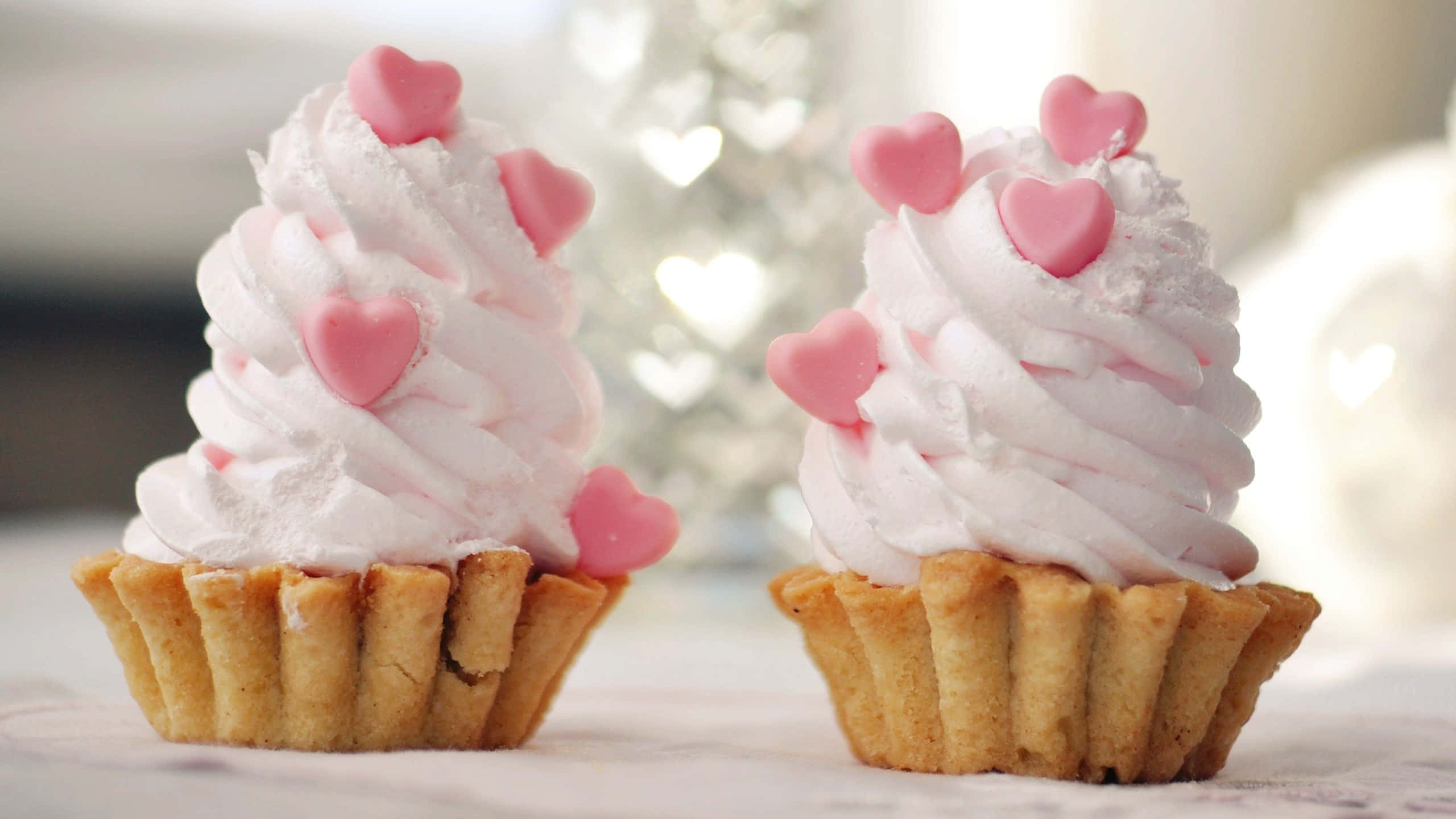 Cute Cupcake 桌布 壁紙 — 兩個精緻的心形頂部杯子蛋糕，搭配 fluffy 粉紅色糖霜，旁邊有一棵柔和模糊的心形樹。