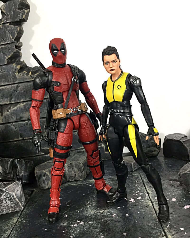 Deadpool And Negasonic Teenage Warhead 桌布 壁紙 — 兩個精緻的死侍和模仿貓動作人偶在破碎的石頭背景下動態擺姿勢。