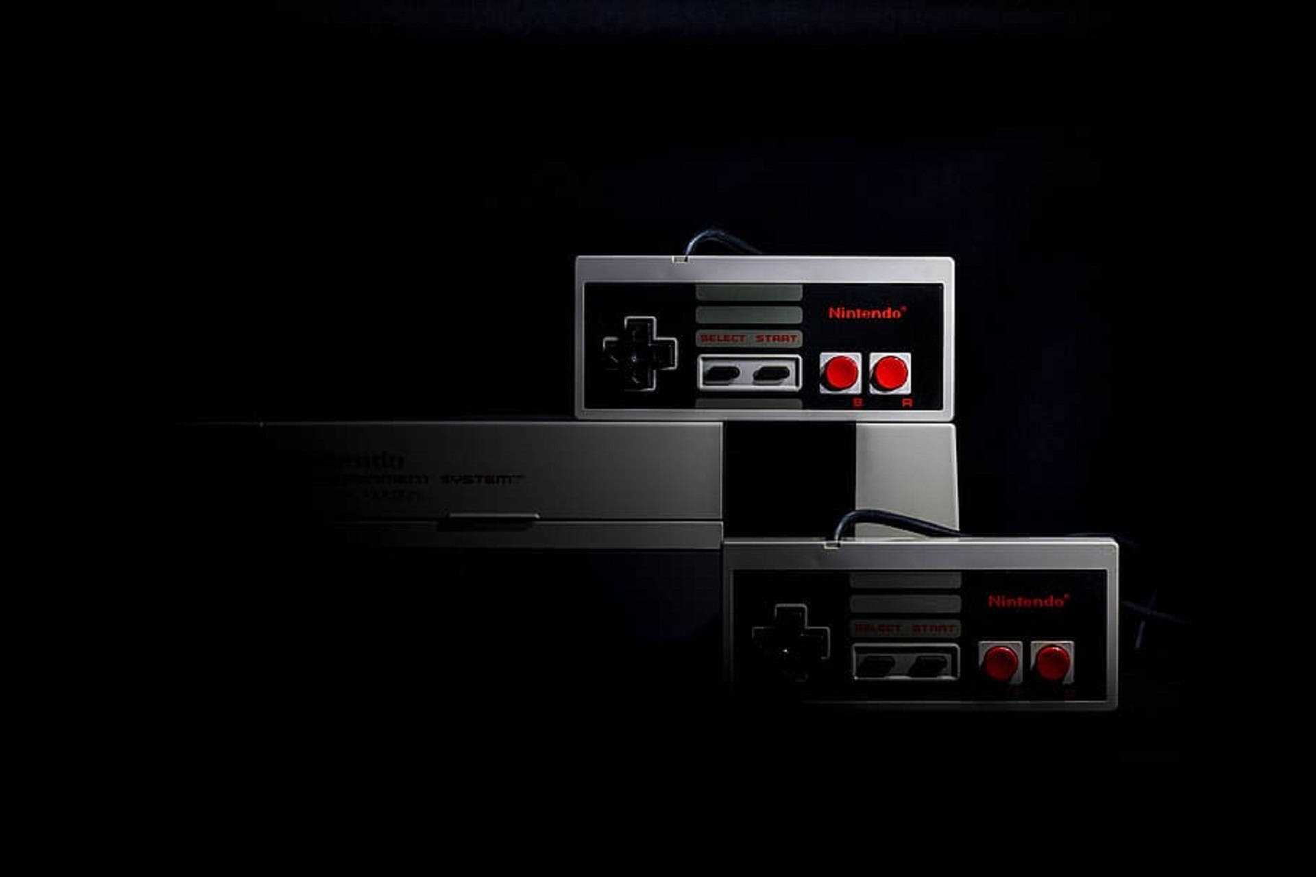 紅白機 桌布 壁紙 — 兩個經典 Nintendo Entertainment System 控制器和主機堆疊在黑色背景上，帶有戲劇性的燈光。