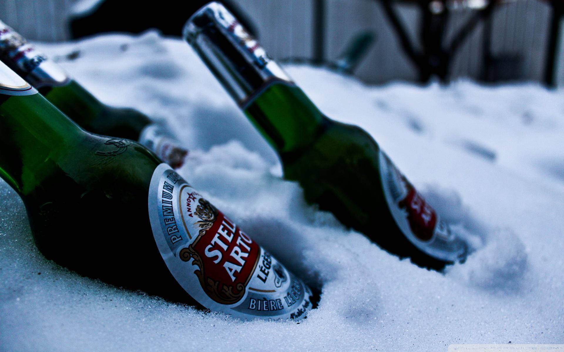 Beer 桌布 壁紙 — 兩個綠色啤酒瓶半埋在新鮮雪中，在冷藍光下可見結霜的標籤。
