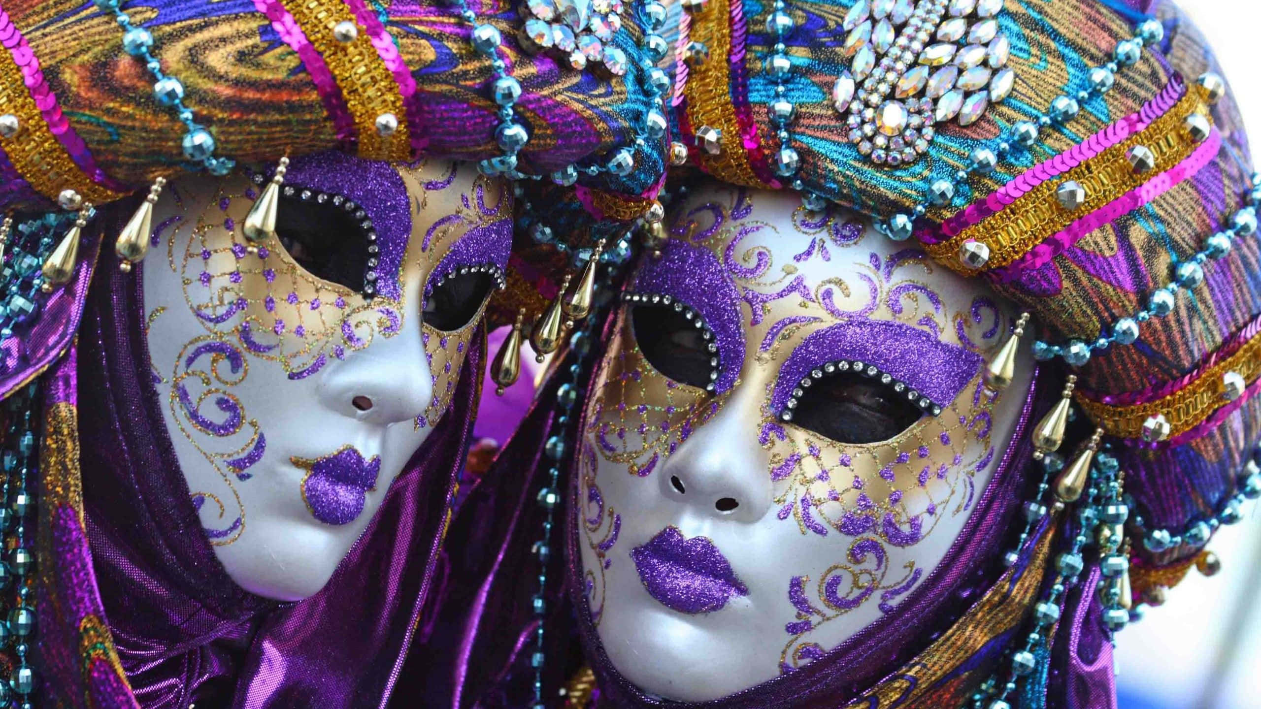 Mardi Gras 桌布 壁紙 — 兩個華麗的威尼斯面具，飾有紫色金色珠子和閃閃發光的寶石，在充滿活力的嘉年華輝煌中向前凝視。