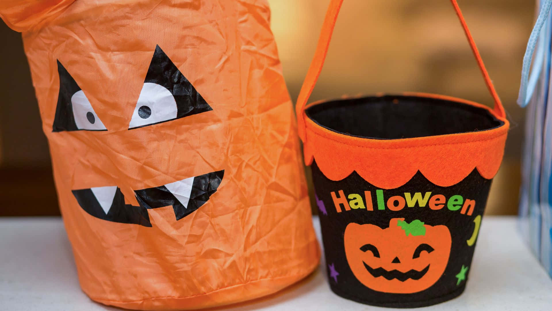 Trick Or Treat Bags 桌布 壁紙 — 兩個萬聖節不給糖就搗蛋桶，一個是傑克南瓜燈造型，帶有凸眼，另一個是黑色，帶橙色飾邊和節日文字。