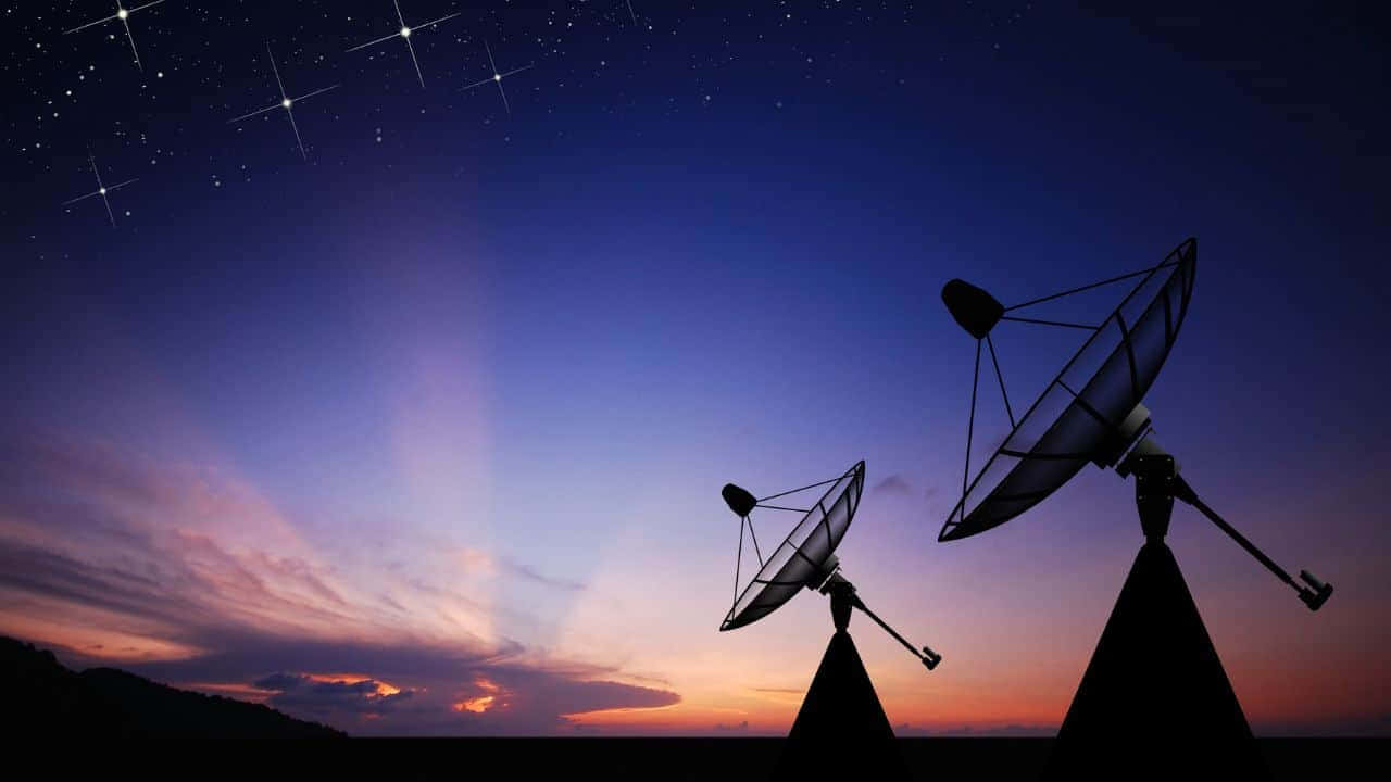 Satellite Technology 桌布 壁紙 — 兩個衛星天線在紫色、橙色和星星交織的暮色天空襯托下呈現剪影。