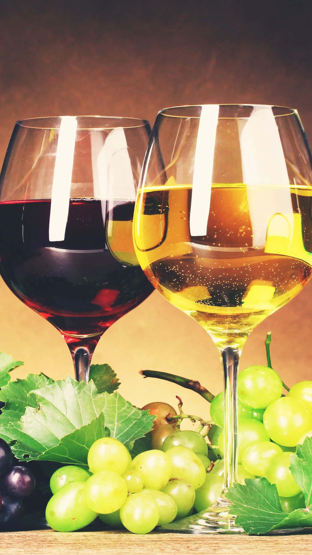White Wine 桌布 壁紙 — 兩個裝滿紅酒和白酒的酒杯放在木質表面上，旁邊是新鮮的綠色和紫色葡萄及葉子。